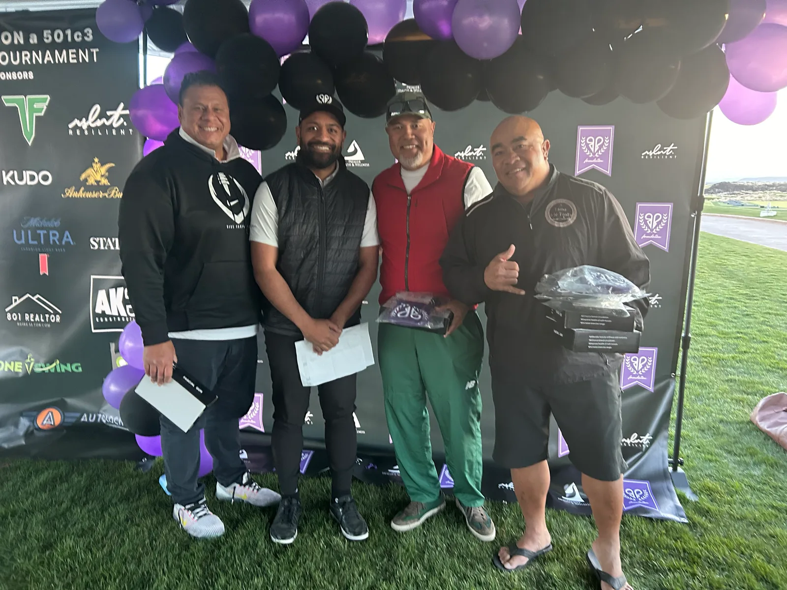 Four guests together beneath purple and black balloons at a Foundation gathering